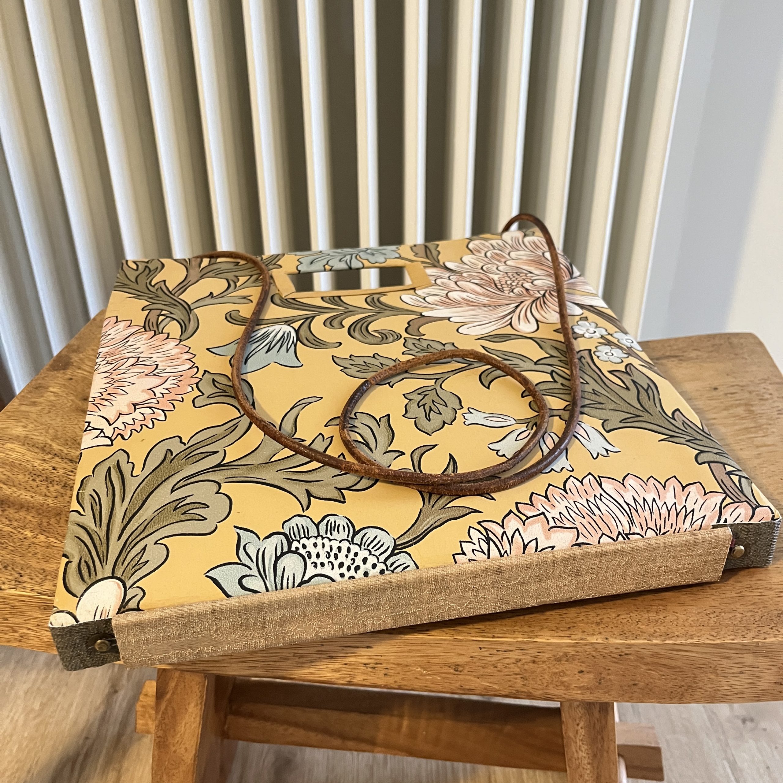 blumige Tasche auf Hocker vor Heizung