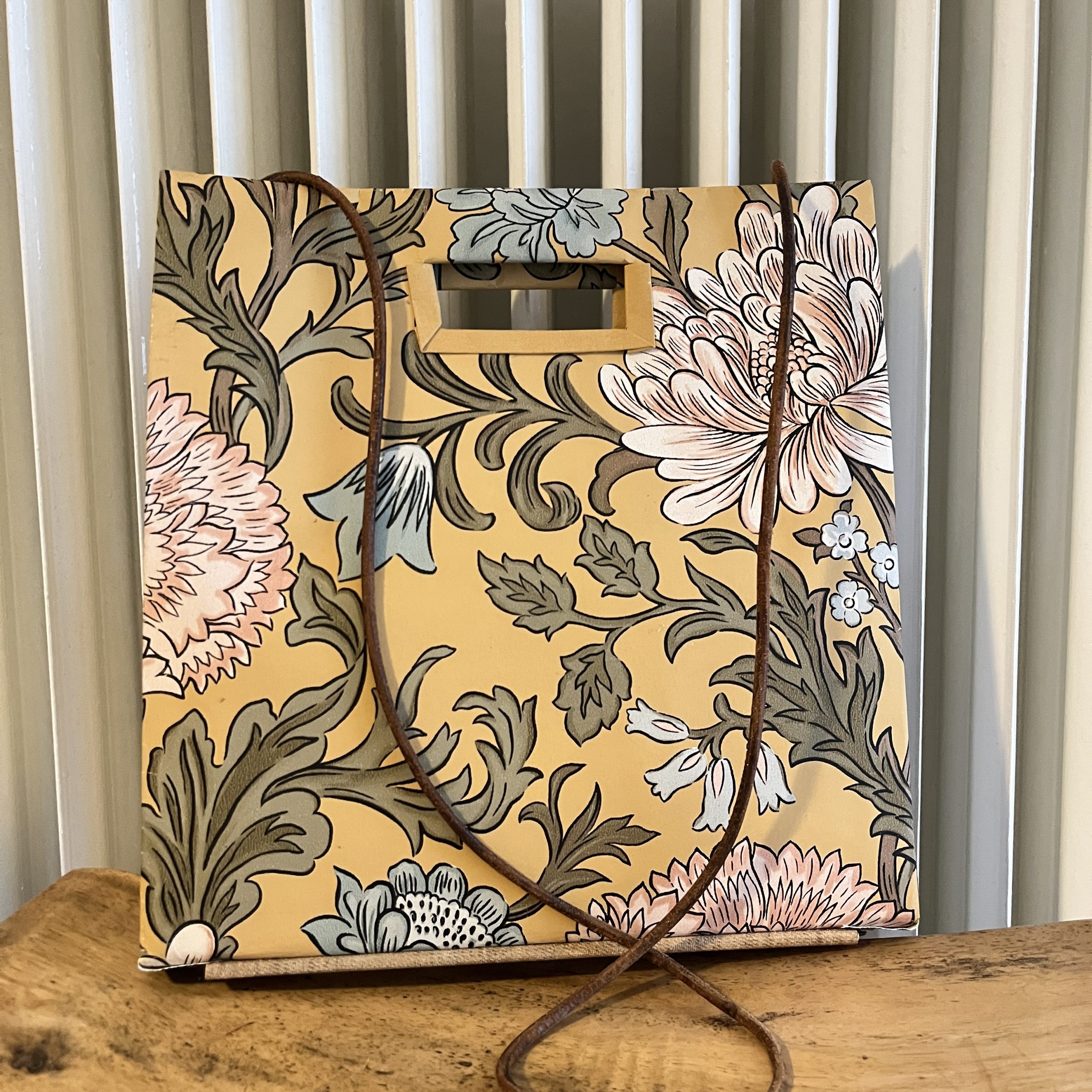 blumige, quadratische Tasche mit Lederriemen vor Heizung